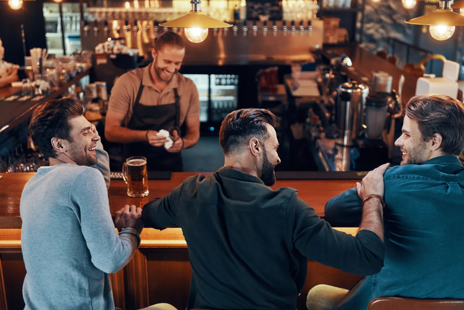 three people at a bar counter talking while a bartender works behind it — equipment breakdown for kitchen plant