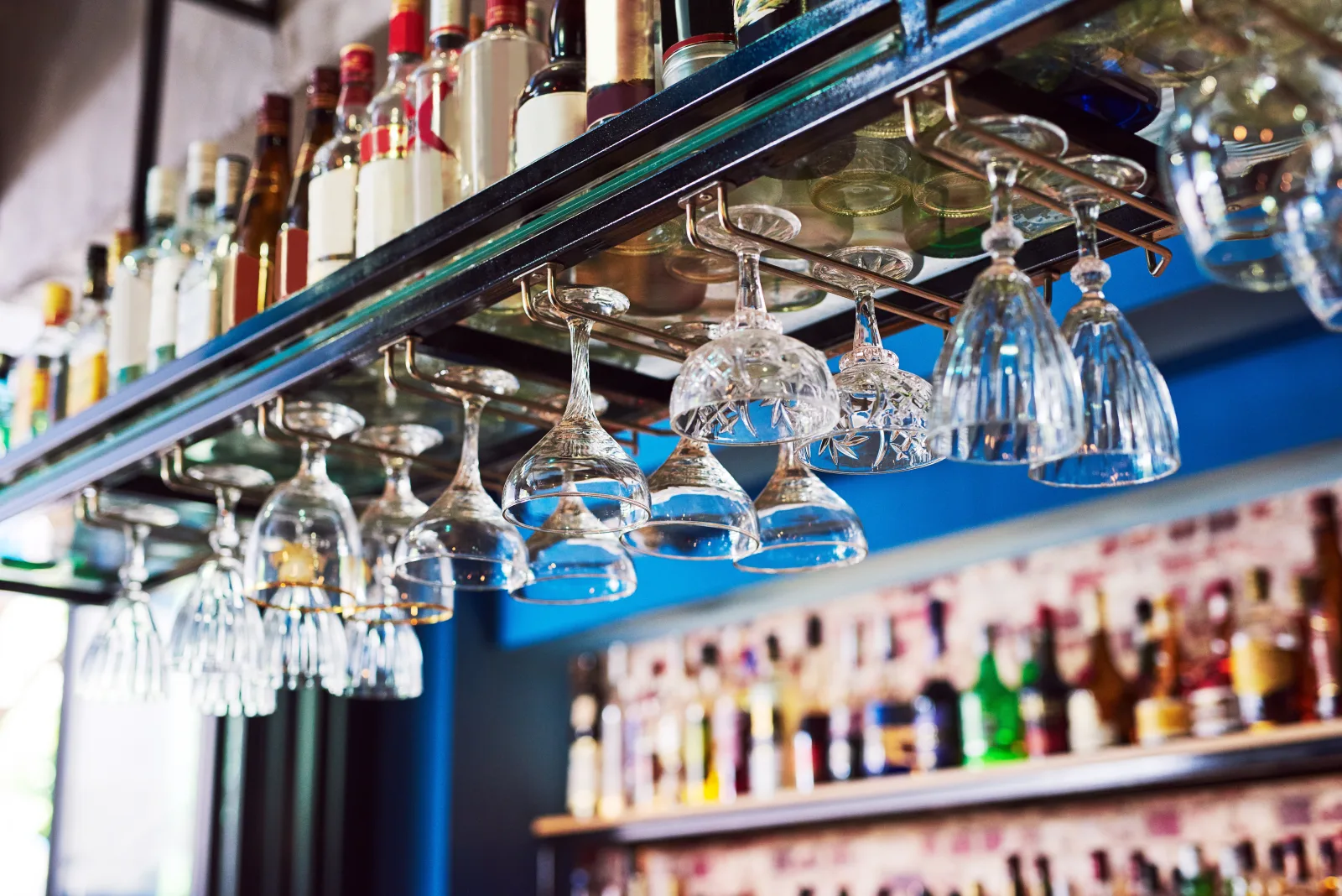 a row of hanging stemware above a brightly lit bottle display — bar insurance in Illinois