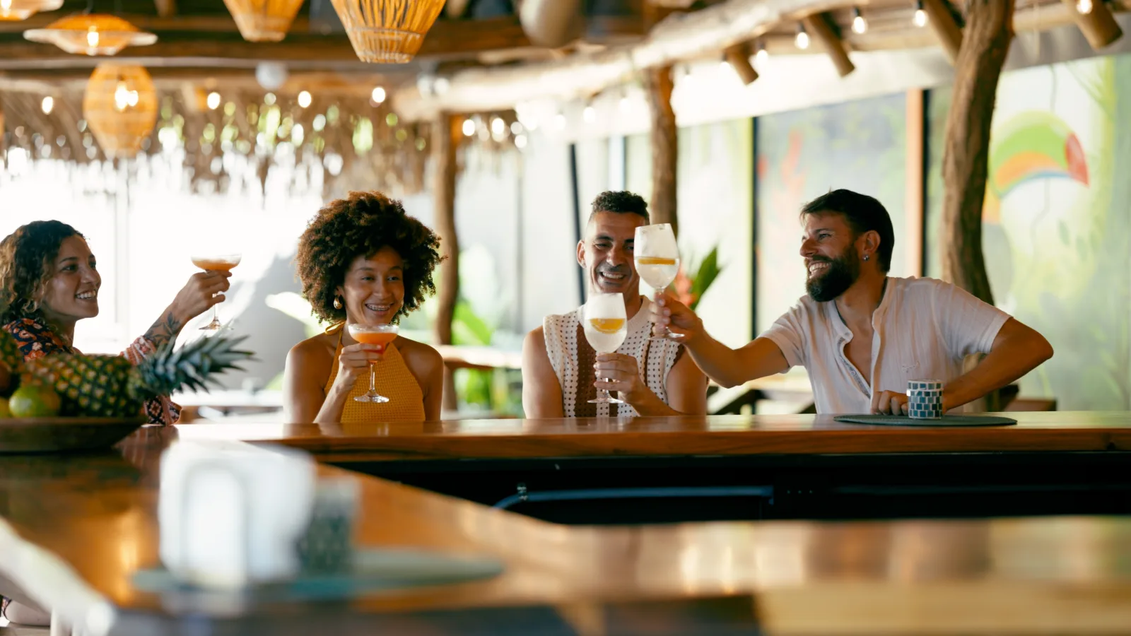 four people raising drinks at an outdoor bar with a pineapple in the foreground — bar insurance in Wisconsin