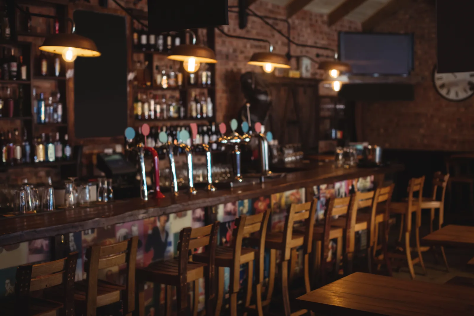 a long bar counter with taps and stools in a dim room — bar insurance in Wyoming