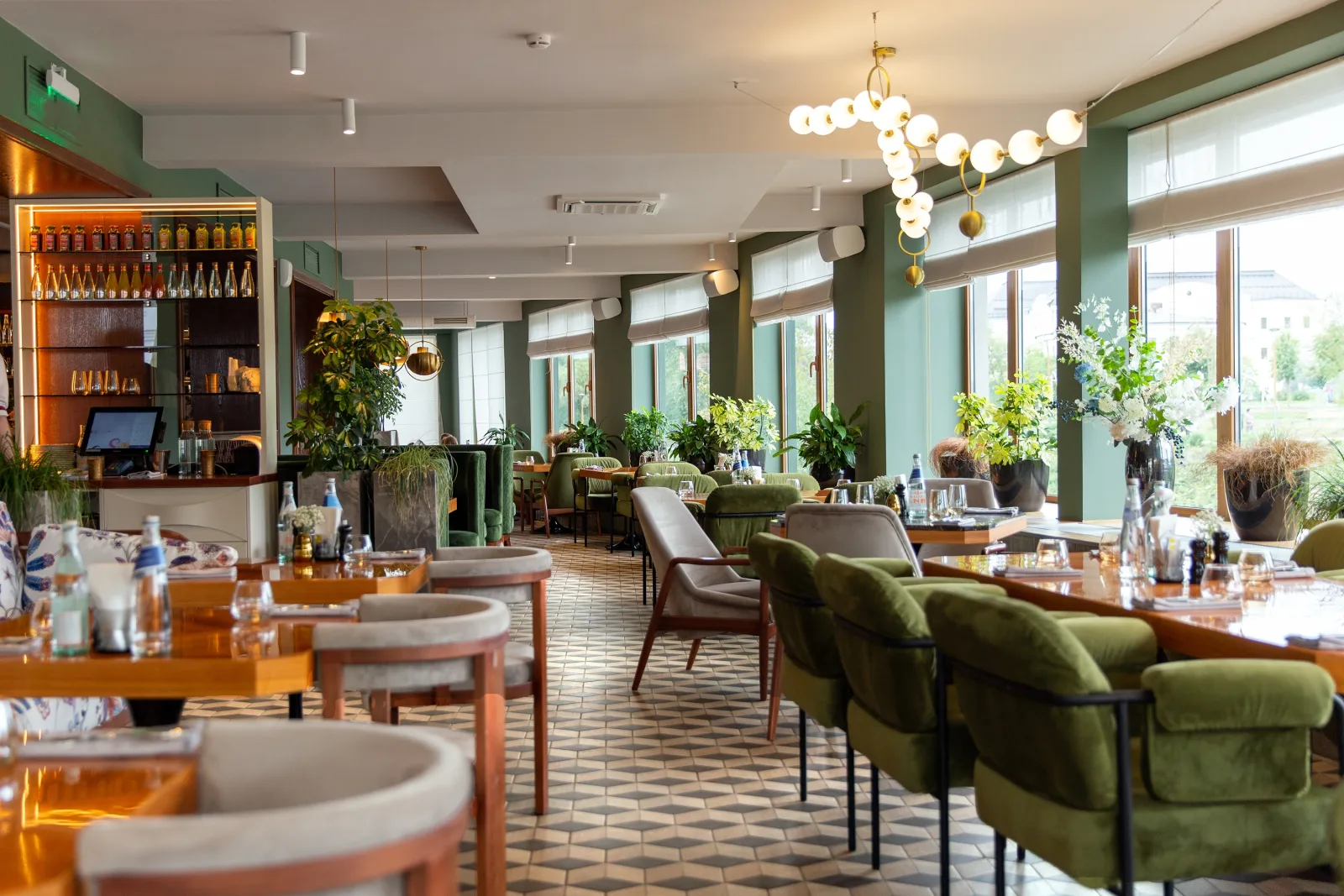 a bright dining room with green upholstered banquettes, patterned tile flooring and pendant lights along a window wall — restaurant and bar insurance for operators in 48 states