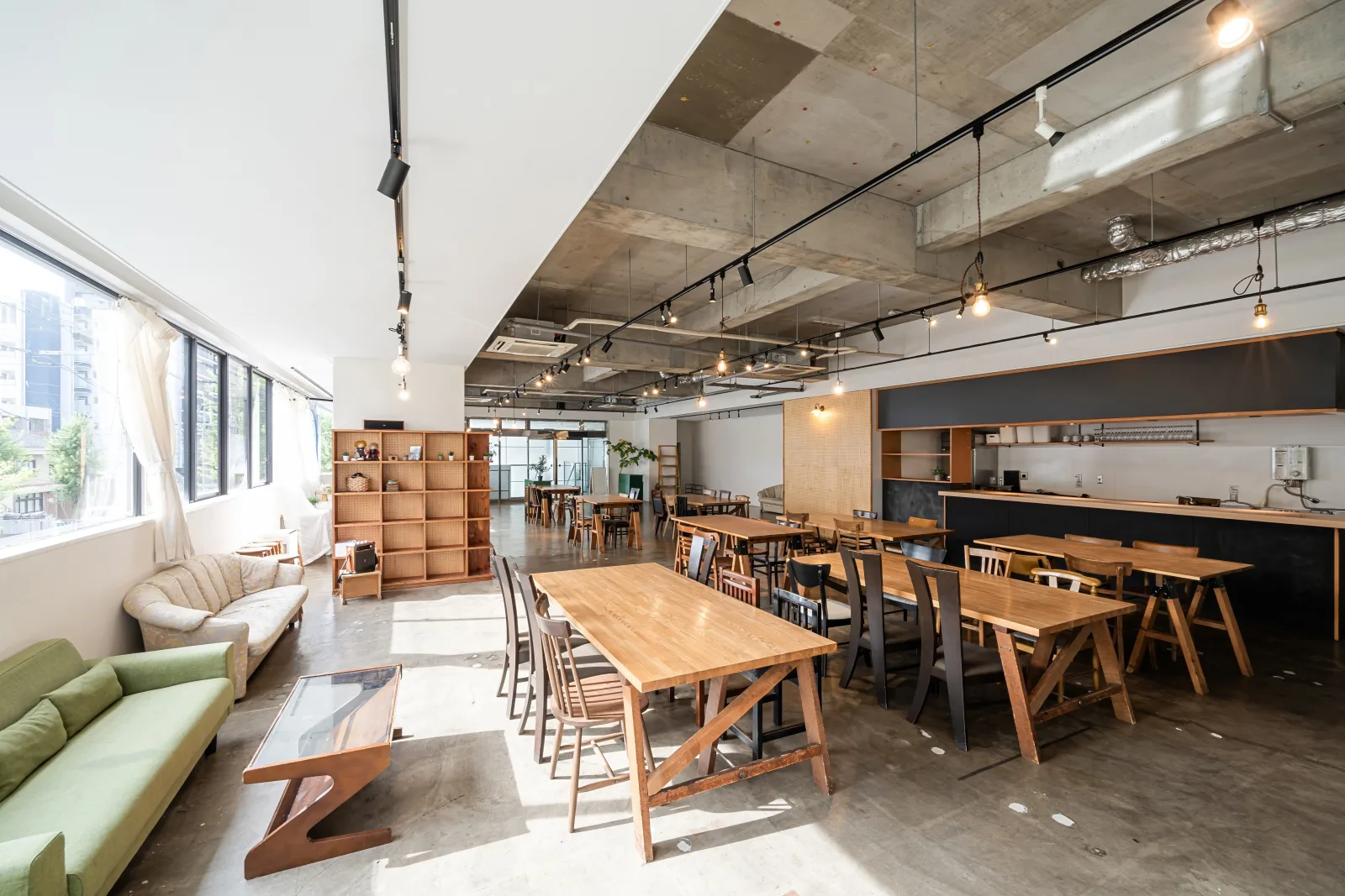 a long communal table in a daylit room with exposed ceiling services and bench seating — umbrella and excess liability