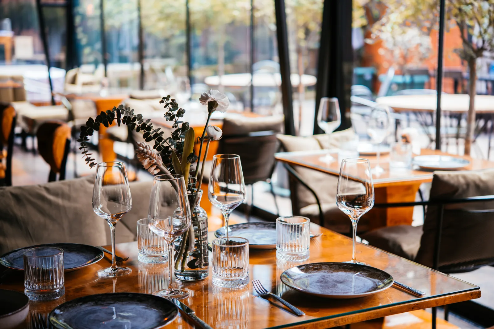 a laid table with wine glasses, dark plates and a dried floral arrangement — restaurant insurance