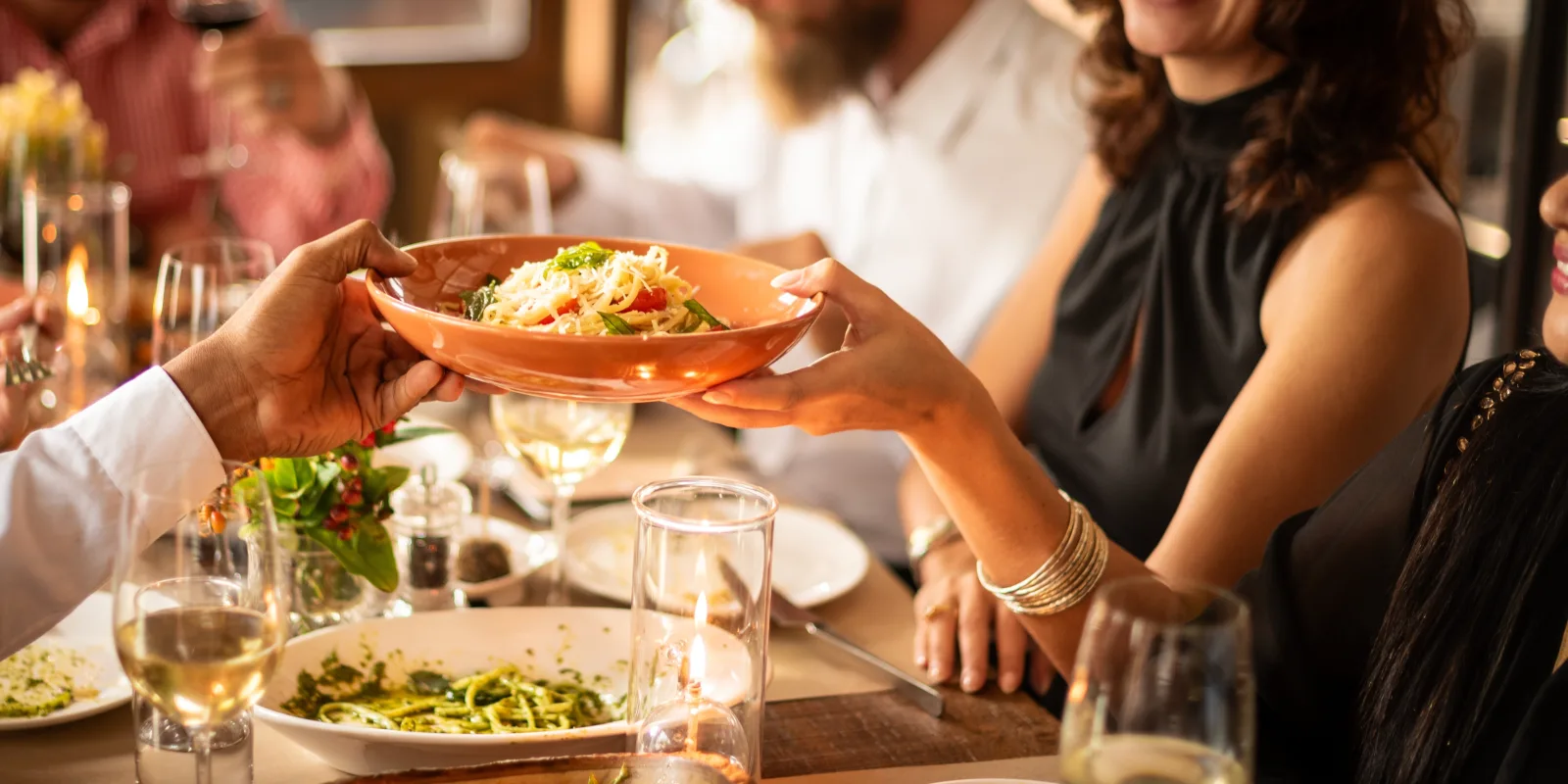 a person passing a bowl across a table set with plates and wine glasses — restaurant insurance in New Jersey